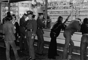 Jugendliche, teilweise in Uniform der NVA, an einem Schießstand auf dem Rummelplatz