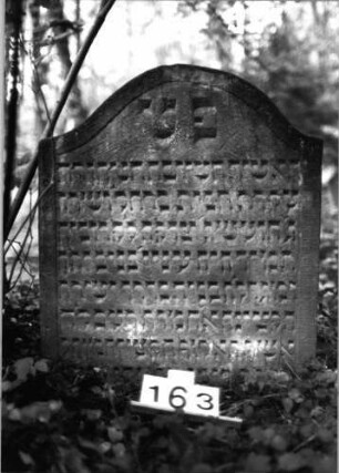 Grabstein 163 (Index: 99803190) Material: Sandstein Zustand: eingesunken Maße HxBxT: 81x69x11 cm Beschreibung: Stele mit Karniesbogen und profiliertem Rand: Grabstein 163