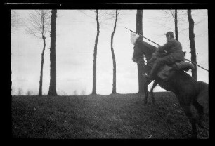 Nicht identifizierbare Ortschaft in Nordfrankreich oder Belgien: Ulan zu Pferd mit Lanze beim Überwinden einer Böschung (Seitansicht)