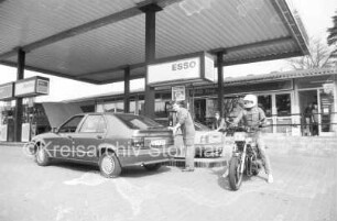 Sandesneben (Kreis Herzogtum Lauenburg): Tankstelle Esso-Station Osterhoff: Hauptstraße, bei Abzweig Blumenstraße: an Zapfsäulen: Serviceleiter Thomas Elsler bei Pkw: Motorradfahrer: hinten Kunde an Pkw: 14. April 1989