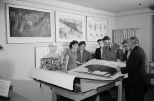 Eine Gruppe von sechs Personen betrachtet auf der Leipziger Herbstmesse 1955 verschiedene grafische Lehrmittel