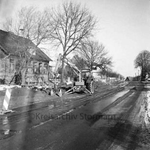 Straßenbau: Barghorster Straße: links Bagger und Baumaterial: hinten rechts und links Wohnhäuser und Bauernhäuser: Winter
