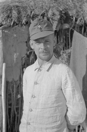 Zweiter Weltkrieg. Zur Einquartierung. Sowjetunion. Angehöriger der deutschen Wehrmacht vor einer Bauernhütte