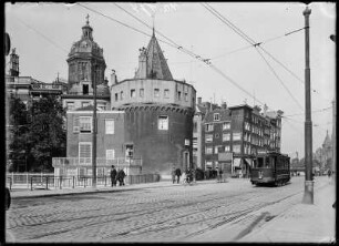 Amsterdam, Niederlande. Straßenansicht mit dem ehemaligen Wehrturm Schreierstoren. Im Hintergrund der Turm der Basilika St. Nikolaus