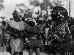 Vorführung eines Tanzes : Vorführung eines Tanzes in Dilolo. Die Personen tragen Masken, Kopf- und Körperbedeckungen.