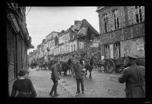 Bapaume (Dep. Pas-de-Calais, Frankreich): Pferdegespanne auf einer gepflasterten Straße vor einer Häuserzeile mit einer Gebäuderuine (Nahaufnahme) ("Straße während der Sommeschlacht")