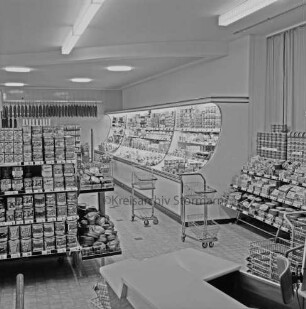 Peters Delikatessen: Mühlenstraße, Ecke Hindenburgstraße: Feinkostgeschäft: Innenaufnahme: Blick in Verkaufsraum: Regale mit Waren, Kühltheke, Einkaufswagen, Einkaufskörbe: vorne Kasse