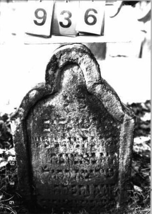 Grabstein 936 (Index: 99753175) Material: Sandstein Zustand: verwitt/Stele eingesunken Maße HxBxT: 68x45x19 cm Beschreibung: Stele, geschwungen eingezogener Rundbogenabschluß: Grabstein 936
