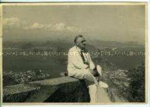 Richard Fleischhut mit Kamera und Dienstmütze "Photograph" in Rio de Janeiro, Brasilien, im Hintergrund der Zuckerhut