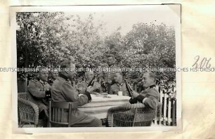 Angehörige der Ordnungspolizei mit Getränken an einem Tisch im Garten