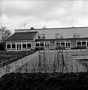 Reesenbüttel: evangelischer Kindergarten: Wulfsdorfer Weg: vor Fertigstellung: Außenaufnahme: Rückfront: davor Freifläche mit Spielgeräten, Plattenweg, Anpflanzungen
