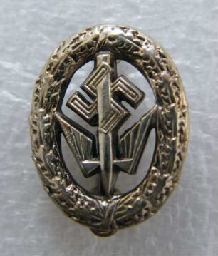 Leistungsabzeichen für Handelskammerprüflinge in Silber Deutsche Stenografenschaft (mit Broschennadel) : Sammlung Beinhorn. Leistungsabzeichen für Handelskammerprüflinge in Silber Deutsche Stenografenschaft (geflügelte Feder und Hakenkreuz im Eichenkranz, mit Broschennadel; rückseitig: Ges. Gesch.). Metall, versilbert; Maße 18 x 14 mm (1933/1943). Dresden: SLUB R c 0184