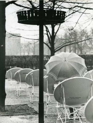 München. In einem Garten-Cafe im Englischen Garten trotzt ein Gast dem Regen. Man nutzt einfach einen Schirm.