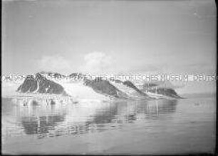 Dunkle Gebirgsreihen mit Schneefurchen am ruhigen Fjord, Nordlandreise, Norwegen