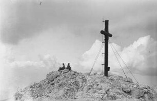 Gipfelkreuz : Zwei Kletterer ruhen sich an einem Gipfelkreuz aus.