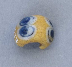 Gelbe Glasperle mit blauem Augenmuster
