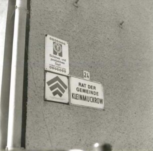 Friedland-Klein-Muckrow. Gemeindeverwaltung, Nr. 24. Schilder "Rat der Gemeinde..." und "Schönes und produktives Dorf..." (vor 1900)