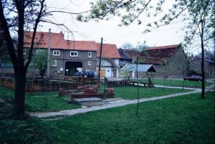 Dorfplatz mit eingezäuntem Teich und Grünanlage