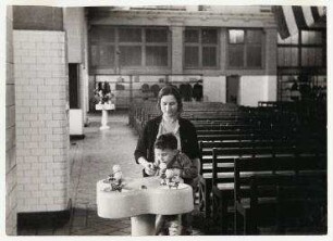 Eine Mutter mit ihrem Kind am Wasserspender auf Ellis Island, New York