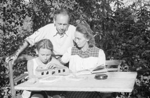 Porträt von Walter Dehmel mit Familie im Garten : Walter Dehmel mit Frau und Enkelsohn beim Spielen an einem Tisch