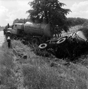 A1: Verkehrsunfall: Tanklastzug fährt in Straßengraben: Unfall-Lastzug schräg in Graben bei Baum: auf Anhänger in Seitenlage Polizist mit Stativ beim Fotografieren: an Böschung Reifenspuren, umgefahrene Sträucher: hinten links Personen an Abschleppwagen mit Kran: links Straße