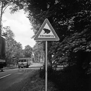 Neuenteich: Landesstraße L 82 Richtung Bargfeld: vorn Mitte Verkehrsschild zu Krötenwanderung: dahinter Büsche: rechts und links am Straßenrand Bäume: links zwei Lkws