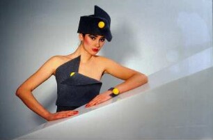 Model in Schaumstoffmode : Model mit schwarzem Schaumstoffhut und -kostüm hinter einem Neonleuchtkörper
