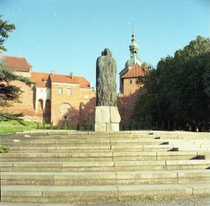 Frombork, Vorplatz zwischen Wasserturm und Domberg mit Kopernikusdenkmal (datiert 1972, Welter; Errichtung 1973). Ansicht mit Dom (1329/1388)