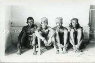 Gruppenbild vierer sitzender Männer der Bangandu vor neutralem Hintergrund
