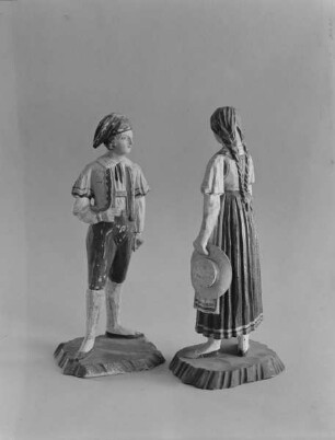 Junger Mann mit Zipfelmütze und Spenzer vor einer jungen Frau