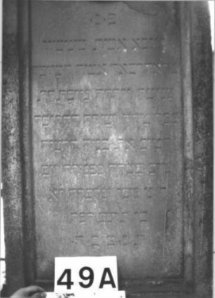 Grabstein 49 (Index: 99898779) Material: Sandstein Zustand: fast vollständig verwittert Maße HxBxT: 209x60x30 cm Beschreibung: aufgesockelte Stele, überkragender Giebelaufsatz mit Eckakroterien, unterer Sockel felsartig gearbeitet Besonderheit: vermutete Identifizierung nach Gräberverzeichnis: Grabstein 49A