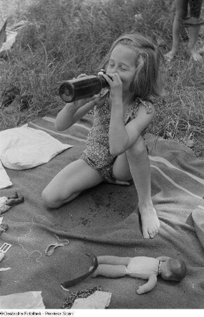 Mädchen auf einer Wiese beim Trinken aus einer Flasche