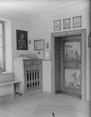 Blick in einen Ausstellungsraum mit Sekretär und bemalter Tür