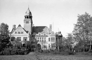 Herrenhaus: Außenansicht von Süden: davor Bäume und Büsche: im Vordergrund Rasenfläche