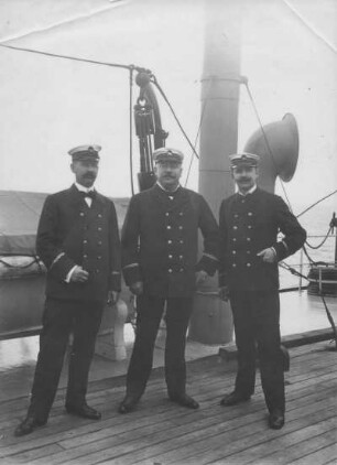Kreuzfahrten der Hamburg-Amerika Linie, um 1910. Drei Besatzungssmitglieder an Deck eines Hochseepassagierdampfers