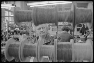VEB Werk für Signal- und Sicherungstechnik Berlin, Bild 2: Ältere Frau durch aufgereihte Drahtspulen hindurch fotografiert. SW-Foto, 1963 © Kurt Schwarz.