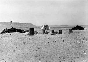 Treibstofftonnen : Blick auf Zelte der Beduinen und Wasser- und Benzinkanister, im Hintergrund Straße von Nalut nach Ghadames.