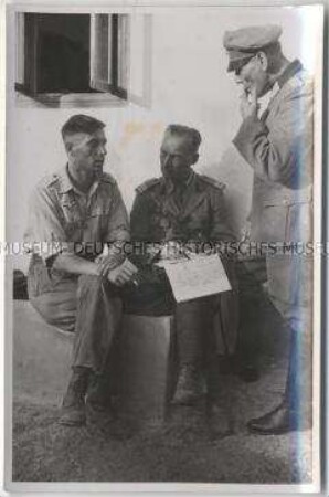 Ein Oberfeldwebel im Gespräch mit einen deutschen Offizier und einem rumänischen Hauptmann