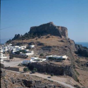 Lindos (Rhodos). Akropolis, Theater, Der Akropolis-Felsen in der Ortschaft. Im Steilhang das antike Theater