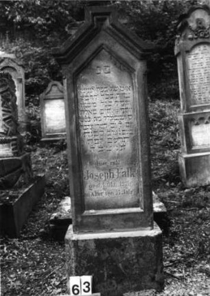 Grabstein 63 (Index: 100079933) Material: Sandstein Zustand: leicht verwittert Maße HxBxT: 152x45x23 cm Beschreibung: Stele, Sockel, eingezogener giebelartiger Abschluß mit Verdachung, rechteckig erhöht, Schrift eingetieft mit giebelartigem Abschluß: Grabstein 63