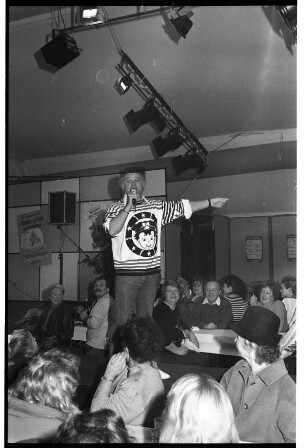 Stormarnia Ahrensburg 1989: Komiker Fips Asmussen steht auf einer Bühne vor Publikum und spricht ins Mikrofon