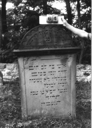 Grabstein 64 (Index: 100110834) Material: Sandstein Zustand: Giebel beschädigt, einzelne Abschieferungen Maße HxBxT: 152x99x24 cm Beschreibung: Stele, Rundbogenabschluß mit Rundbogenfries und Verdachung, Schriftfelder eingetieft: Grabstein 64