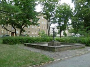 Eisenhüttenstadt: Wohnbebauung Brunnenring (WK I) mit Brunnen (Mädchenfigur)