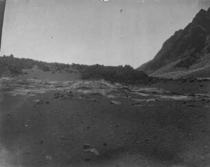 Fladenlava : Blick auf vom Sand verdeckte Fladenlava und im Hintergrund Gebirge.