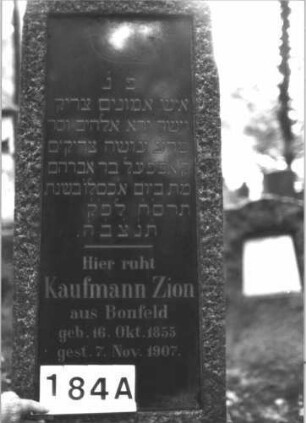 Grabstein 184 (Index: 99899055) Material: Granit Zustand: gut erhalten Maße HxBxT: 200x56x30 cm Beschreibung: Obelisk, Oberfläche grob behauen, eingelassene Schrifttafel, oberhalb der Inschrift eingeritztes Schofar Symbolik: Schofar Besonderheit: kulturhistorisch wertvoll / hist.-wiss. Gründe (Gemeindestellung): Grabstein 184A
