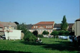 Wiese und anliegende Wohnbauten, hinten das Schütz-Haus