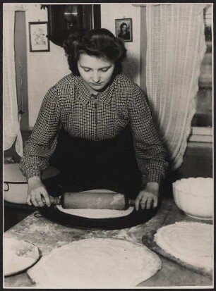 Eine junge Frau beim Ausrollen des Kuchenteigs