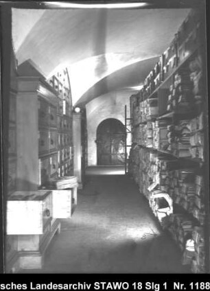 Braunschweigisches Landeshauptarchiv/Niedersächsisches Staatsarchiv in der Alten Kanzlei, Wolfenbüttel [um 1950] Enthält: Gang in einem Magazingeschoss, rechts: Aktenpakete in Regalen, links: Schränke mit Schubladen (Raum 3 ?)
