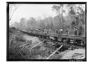 Bauzug mit Arbeitern : Nordthailand. Streckenbau für die Eisenbahn durch den Dschungel. Bauzug mit Arbeitern und Baumaterial auf provisorischer Brücke, 1908/1909