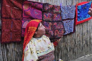 Kuna Yala - Kuna-Indianerin mit Molas : Porträtaufnahme einer Kuna.Indianerin vor den von ihr angefertigten textilen Mola-Kunstwerken mit indianischen Motiven. Aufgenommen am 12. September 2011 auf einer der San Blas Inseln im autonomen Gebiet der Kuna-Indianer vor der Atlantikküste der Republik Panama